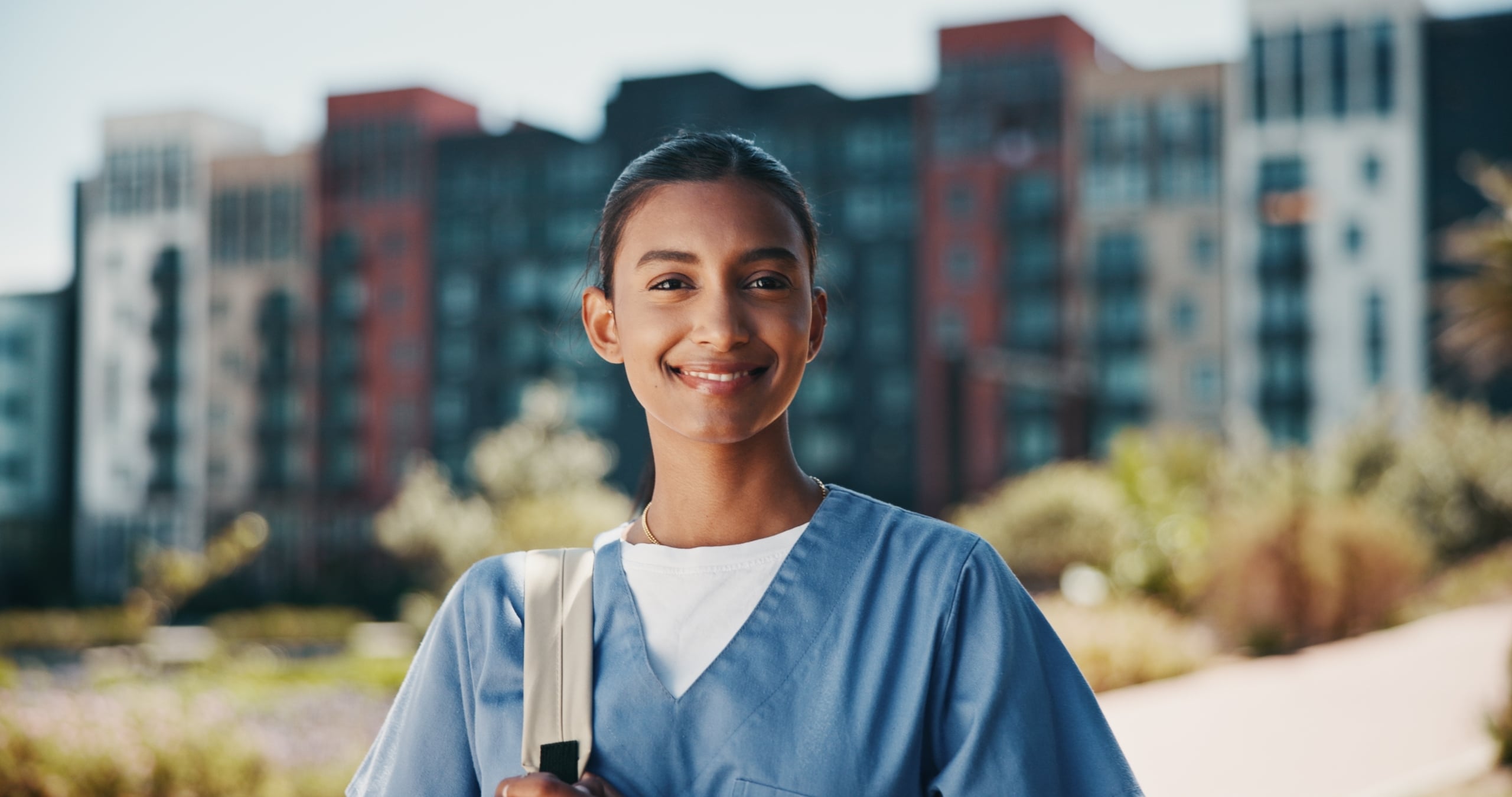 Young Indian nurse standing outside against a cityscape